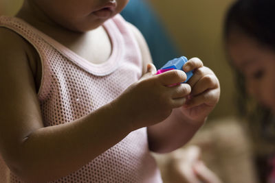 Midsection of baby girl playing with toy at home