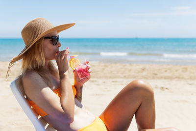 Side view of woman sitting at beach