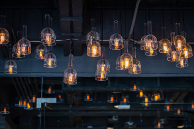 Low angle view of illuminated light bulbs hanging from ceiling