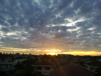 Houses against dramatic sky during sunset