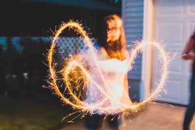 Blurred motion of girl with burning sparkler at night