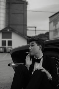 Young man looking away while sitting outdoors