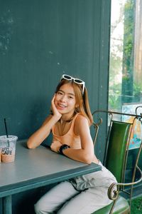 Portrait of a smiling young woman sitting on table