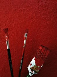 High angle view of paintbrushes on red wall