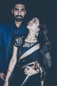 Young couple standing against black background