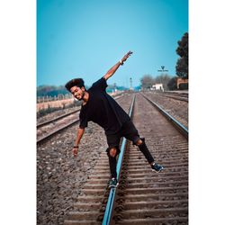 Full length of young man with arms raised against sky