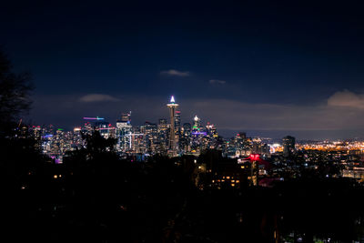 Illuminated buildings in city against sky at night