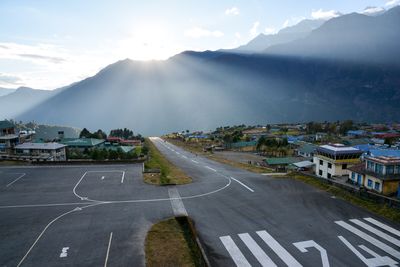 Airport runway by mountains against sky