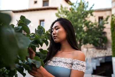 Portrait of a young asian girl admiring the leaves of a tree.