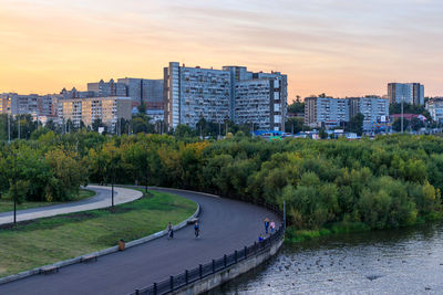 Scenic view of river by buildings against sky during sunset