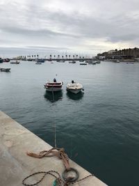 Boats moored in sea against sky in city