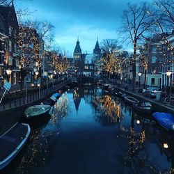 Boats moored in canal at city during dusk