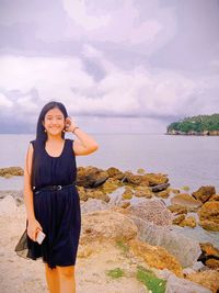 Young woman standing by sea against sky