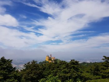 Scenic view of trees and building against sky