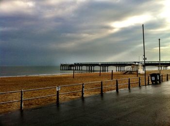 Pier on sea against cloudy sky