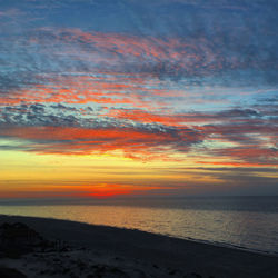 Scenic view of sea against dramatic sky during sunset