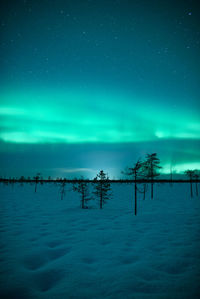 Scenic view of snow covered land against sky during aurora borealis