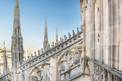 View to spires and statues on roof of duomo through ornate marble fencing. milan, italy