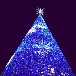 Close-up of illuminated christmas tree against blue sky