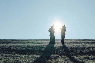 Silhouette people standing on field against sky 