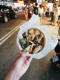 Midsection of woman holding food on street in city