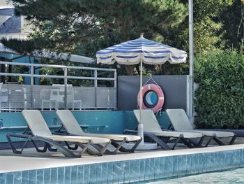 Chairs by swimming pool against trees
