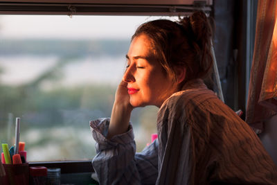 Portrait of young woman looking through window