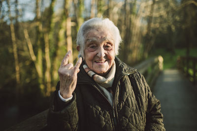 Cheerful elderly woman gesturing horn sign on sunny day