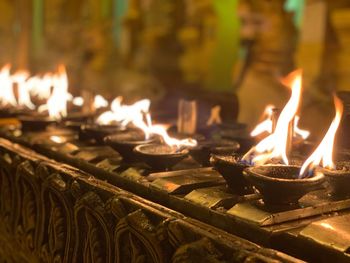 Close-up of burning diyas at temple