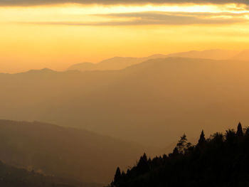 Scenic view of silhouette mountains against orange sky