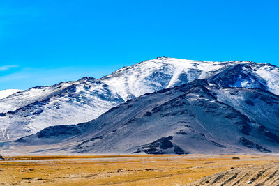 Scenic view of snowcapped mountains against blue sky