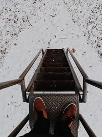 Low section of person standing on ladder during winter