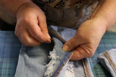 Midsection of woman stitching fabric at table