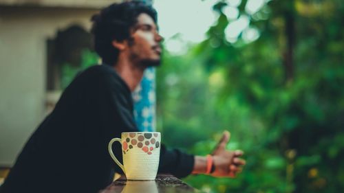 Close-up of coffee cup on railing by man