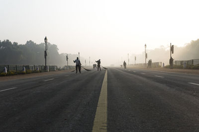 People walking on road against sky