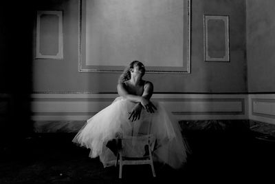 Woman sitting against wall on chair