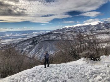Man standing on snowcapped mountain against sky