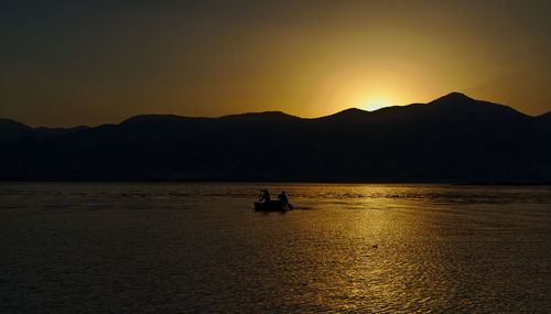 Silhouette boat in sea against sky during sunset