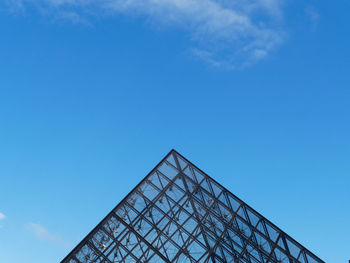 Low angle view of louvre pyramid against blue sky