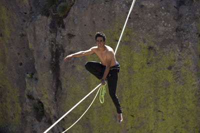 Full length of shirtless man on rope