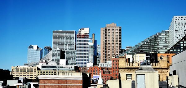 Modern buildings in city against clear blue sky