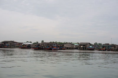 Houses by sea against sky in city