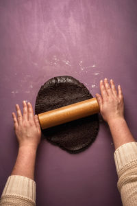 Cropped hands of woman rolling dough on table