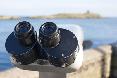 Close-up of coin-operated binoculars at beach against sky