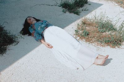 Woman sleeping on footpath in sunny day