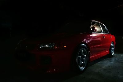 Red car in parking lot at night