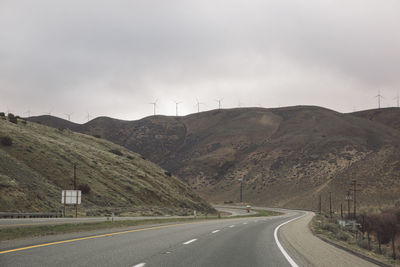 Road by mountains against sky