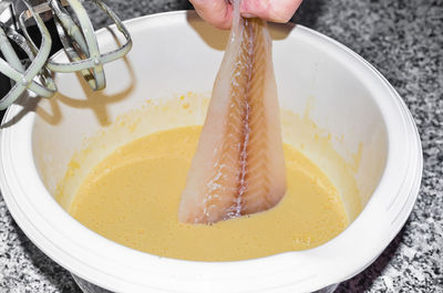 Close-up of hand holding fish in bowl