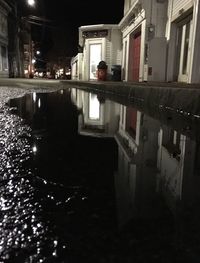 Reflection of building in puddle at night