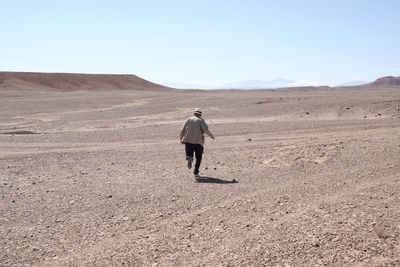 Rear view of man on desert against clear sky
